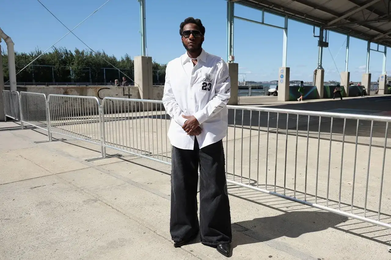 Uomo con pantaloni neri larghi e camicia bianca. Un look audace per chi cerca ispirazione su come abbinare pantaloni neri uomo.