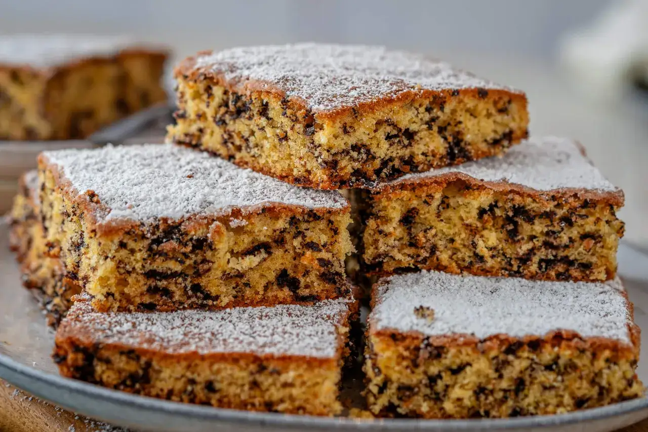 Stapel von saftigen Kuchenstücken mit Schokostückchen, bestäubt mit Puderzucker. Ein schneller Kuchen, der Lust auf mehr macht.
