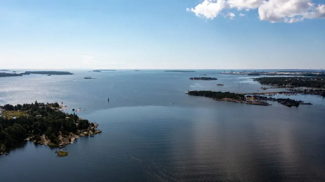 Malownicze fiordy Finlandii, zalesione wyspy i port w oddali.