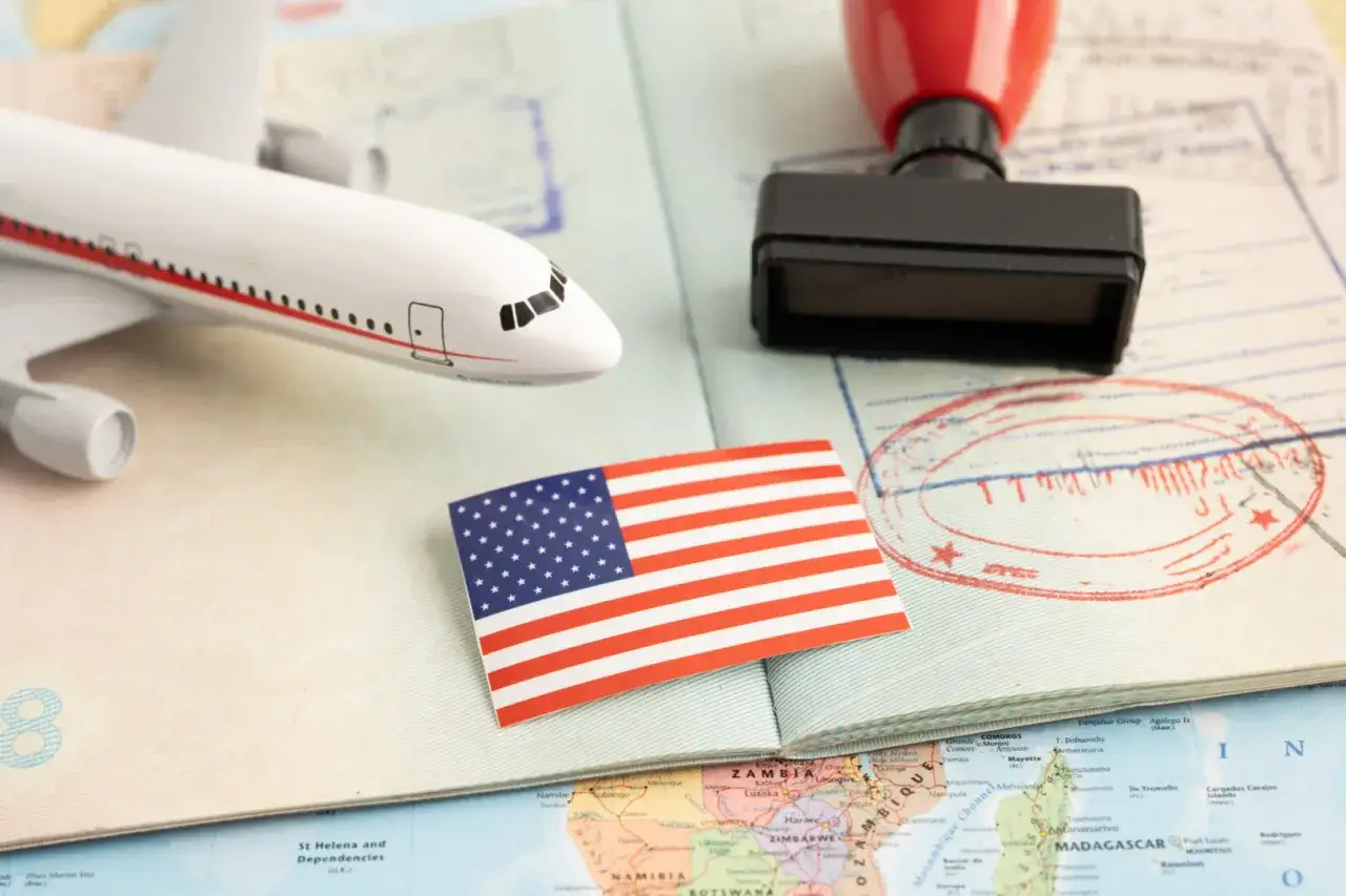 Flugzeugmodell, US-Flagge, Stempel und Pass auf einer Weltkarte. Perfekt f&uuml;r deine USA Reise Checkliste.