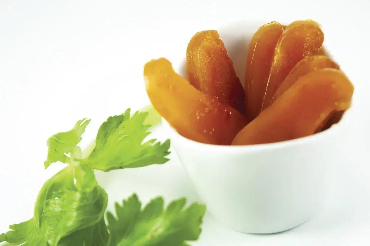 Ein weißes Schälchen mit goldbrauner Bottarga di muggine, daneben frische grüne Petersilie.