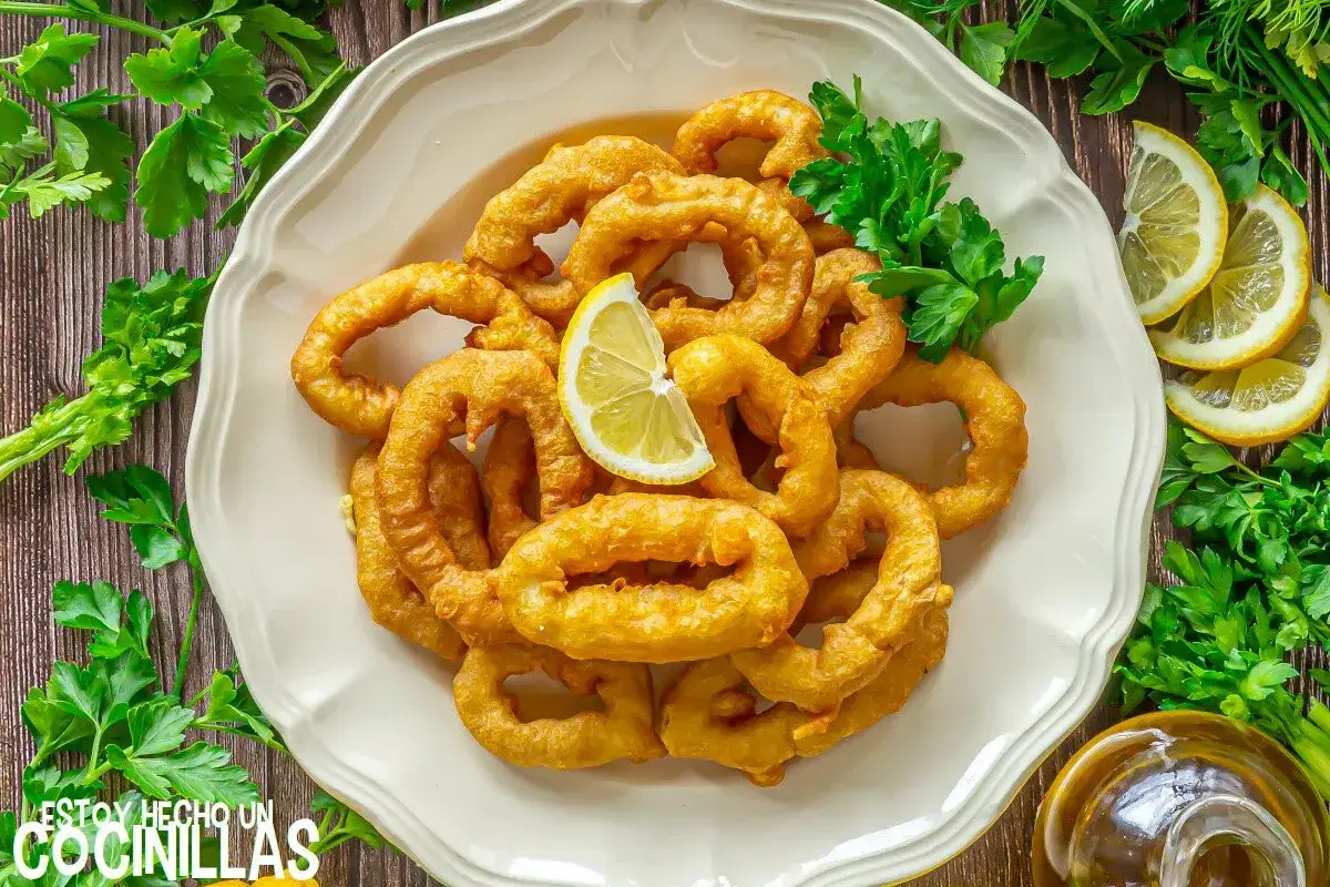 Crujientes calamares a la romana, dorados y listos para disfrutar, adornados con perejil fresco y rodajas de limón.