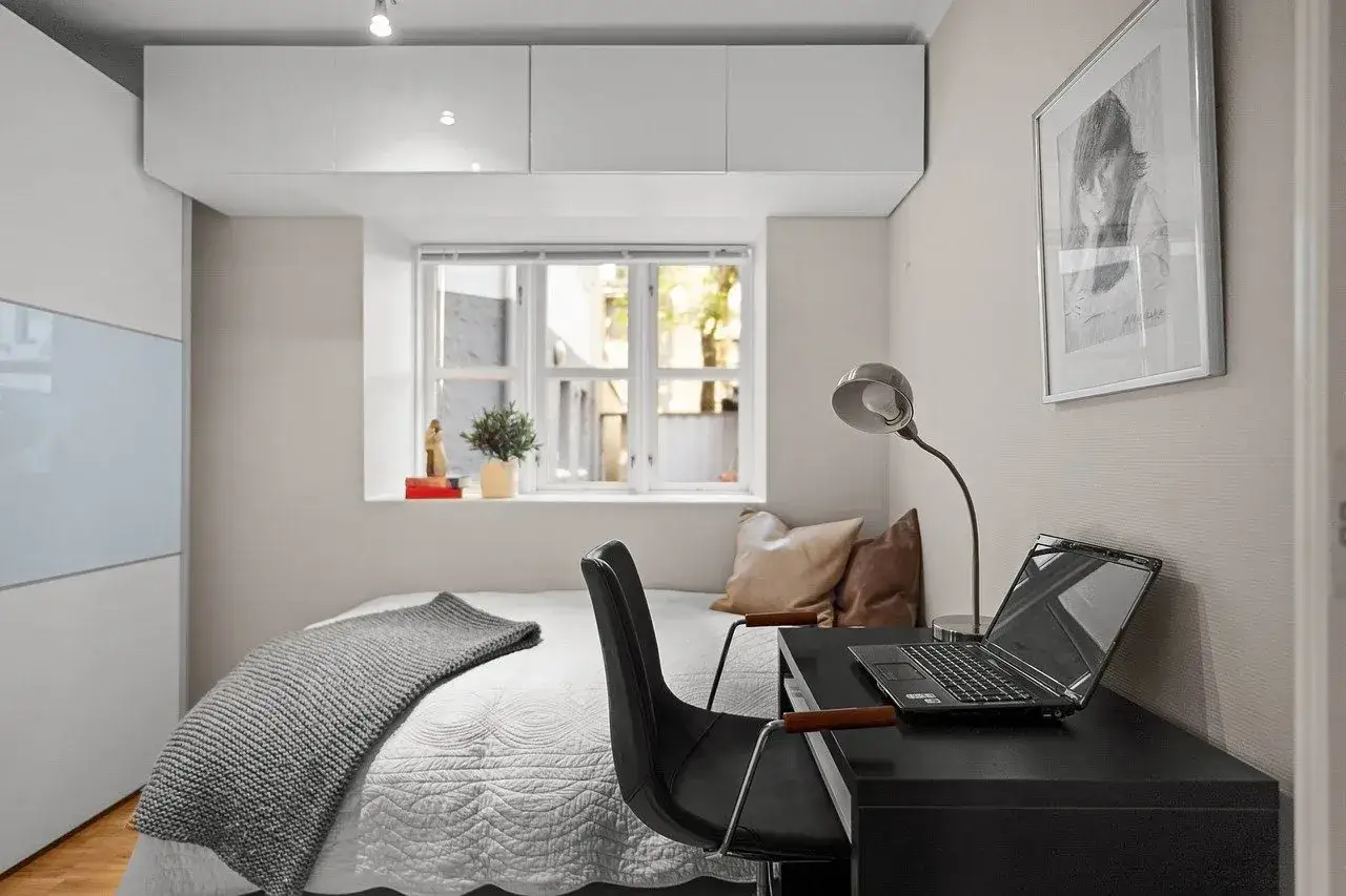 Młodzi Polacy wybierają coliving zamiast kawalerki, bo cenią sobie przestrzeń i wygodę, jak w tym przytulnym pokoju z biurkiem i łóżkiem.