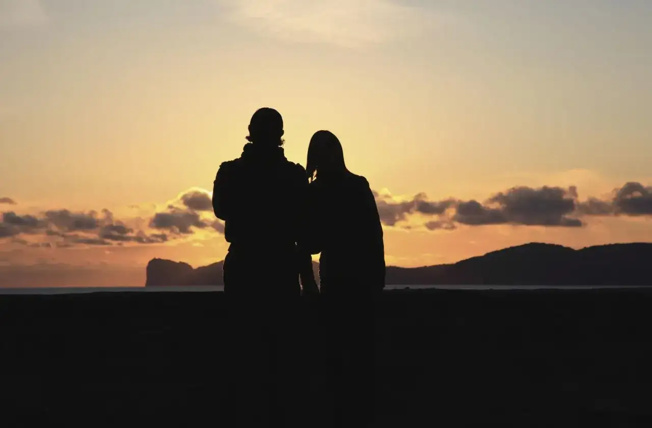 Coppia al tramonto in Sardegna, un luogo perfetto dove andare in vacanza per momenti romantici.