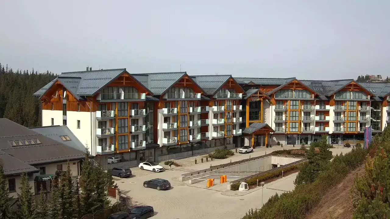 Widok z kamer w Bukowinie Tatrzańskiej na nowoczesny hotel z drewnianymi elementami i parkingiem.