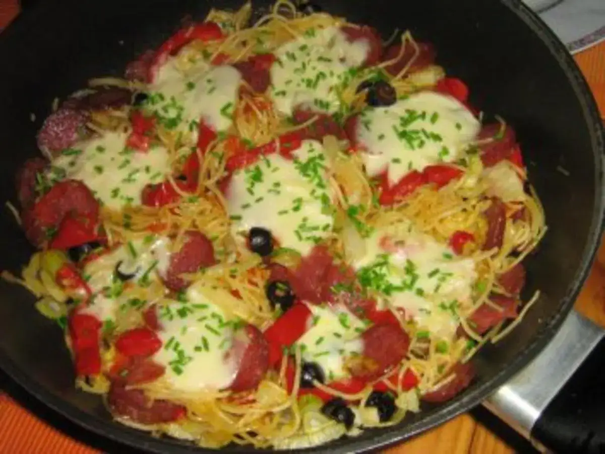 Spaghetti mit Salami, Paprika, Oliven und geschmolzenem K&auml;se, bestreut mit Schnittlauch. Ein herzhaftes Gericht, das an Fenchel erinnert.