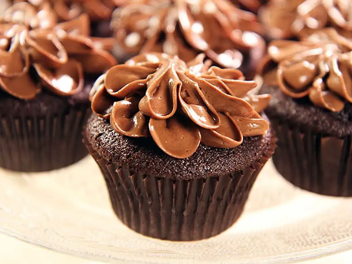 Chokladmuffins med fluffig frosting till chokladmuffins. En närbild visar detaljerna i den krämiga chokladglasyren som pryder de mörka muffinsarna.