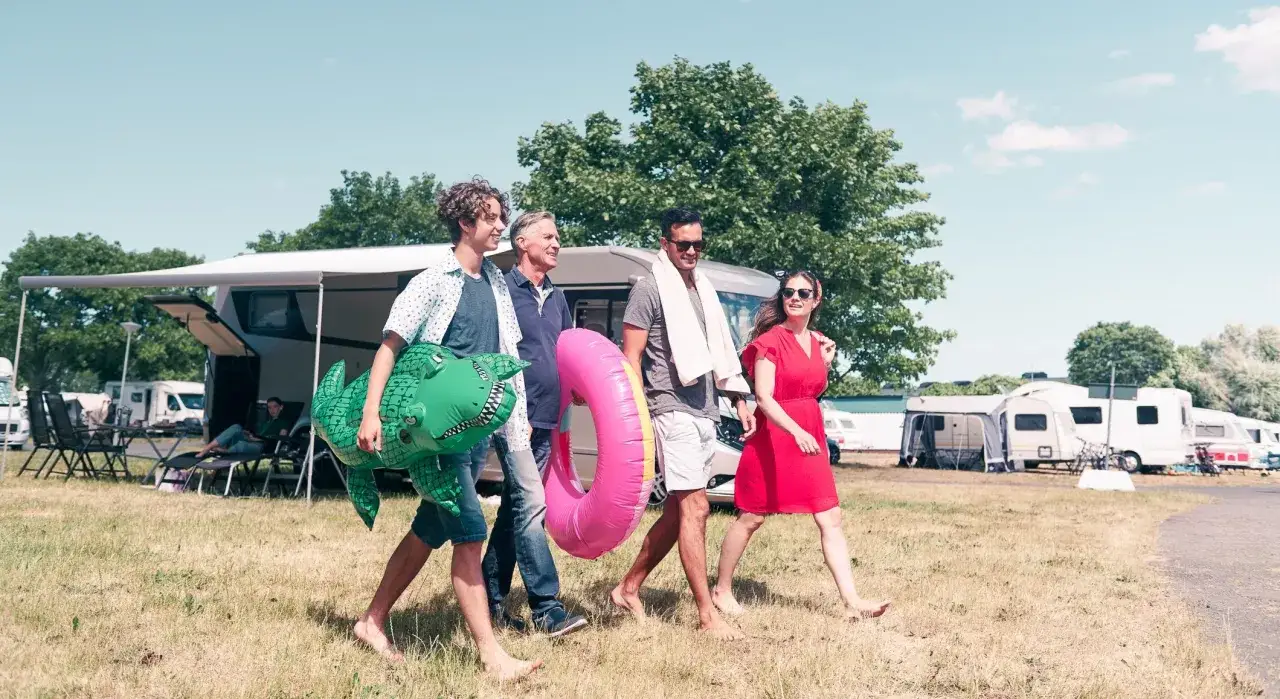 Rodzina z niemowlakiem w Chorwacji, idzie na plażę z dmuchanym krokodylem i kołem ratunkowym.