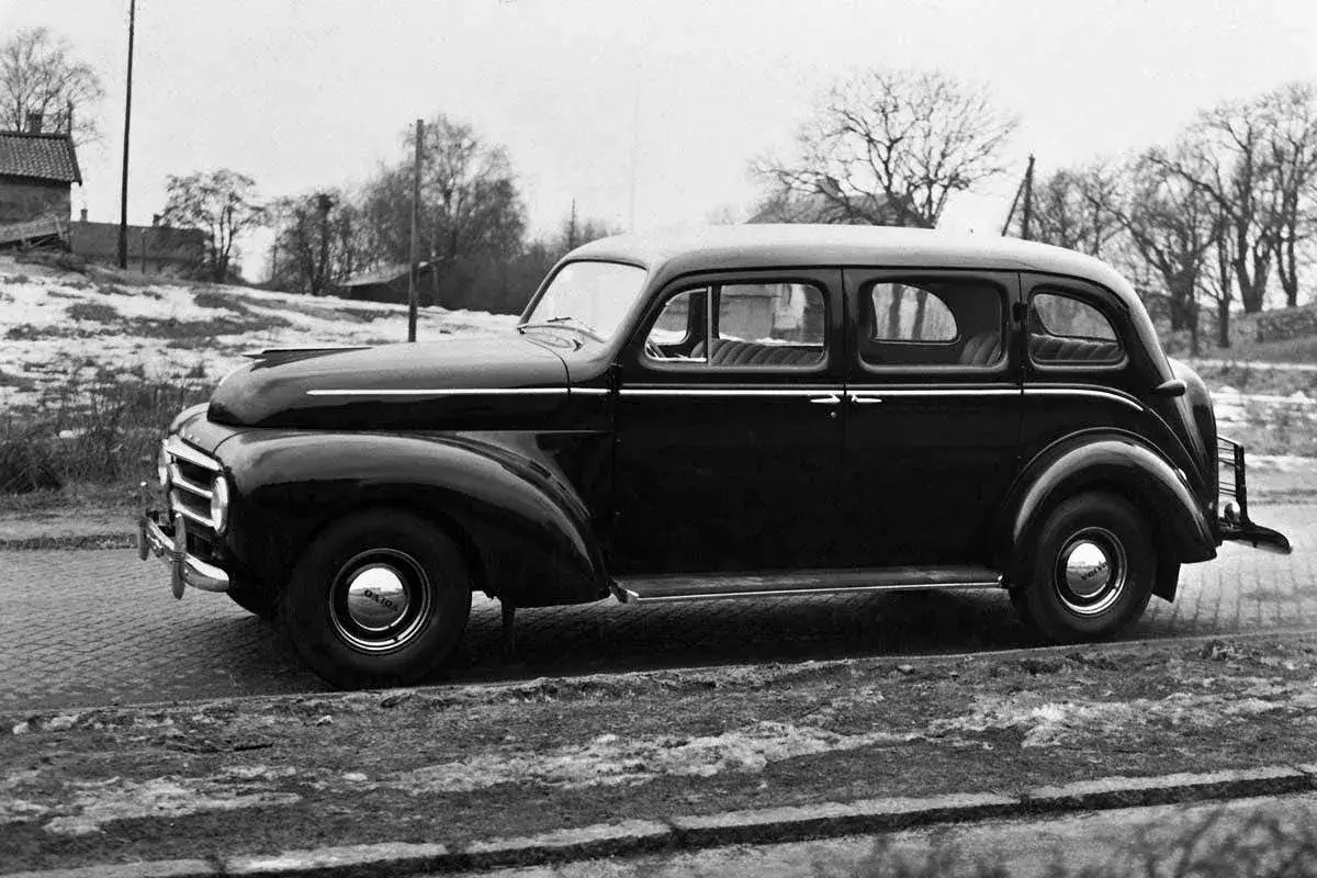 En svart, klassisk Volvo PV 51 står parkerad vid en snötäckt väg. En riktig sugga bil för sin tid.