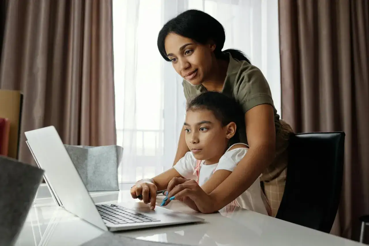 Mama pomaga córce w nauce online, pokazując, jak płaci się za nauczanie indywidualne.