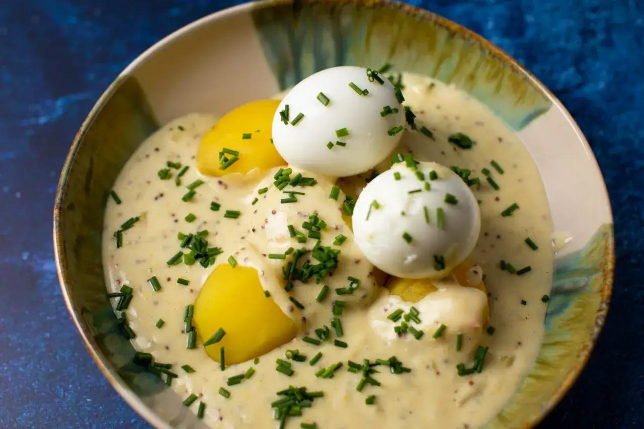 Schmackhaftes Senfeier Rezept: Gekochte Eier und Kartoffeln in cremiger Senfsauce, garniert mit Schnittlauch.