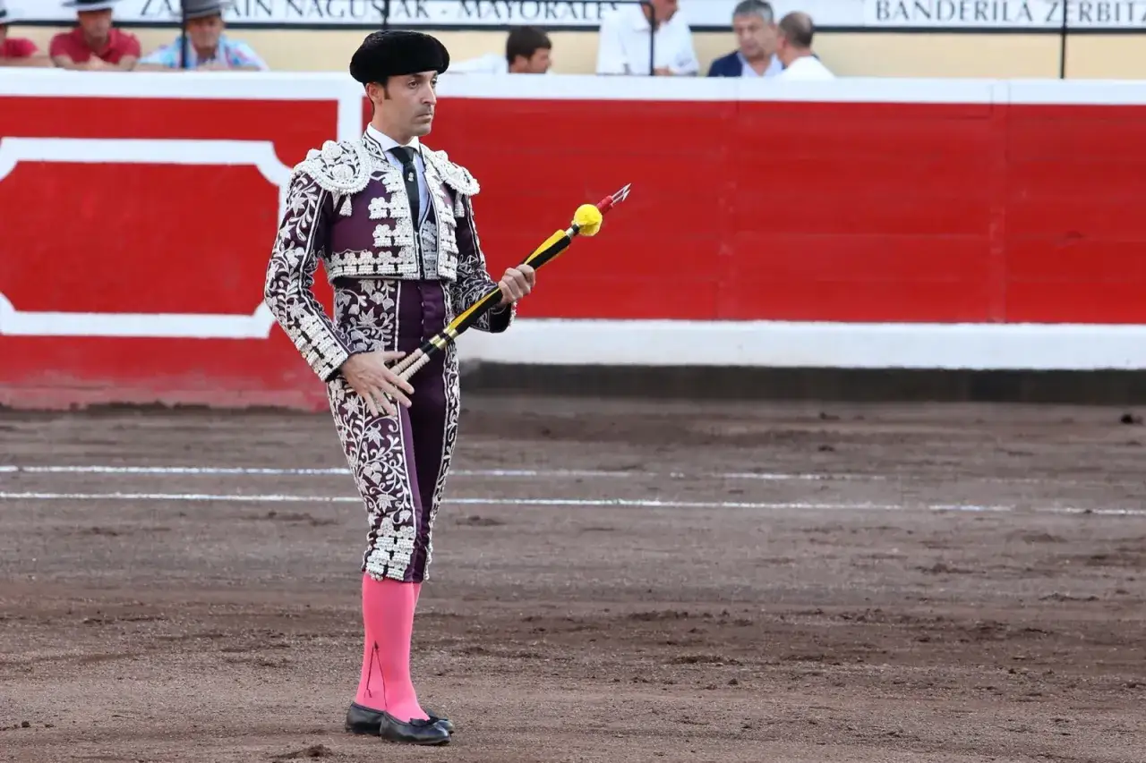Torero con traje de luces morado y blanco, listo para clavar la viruta banderillero.