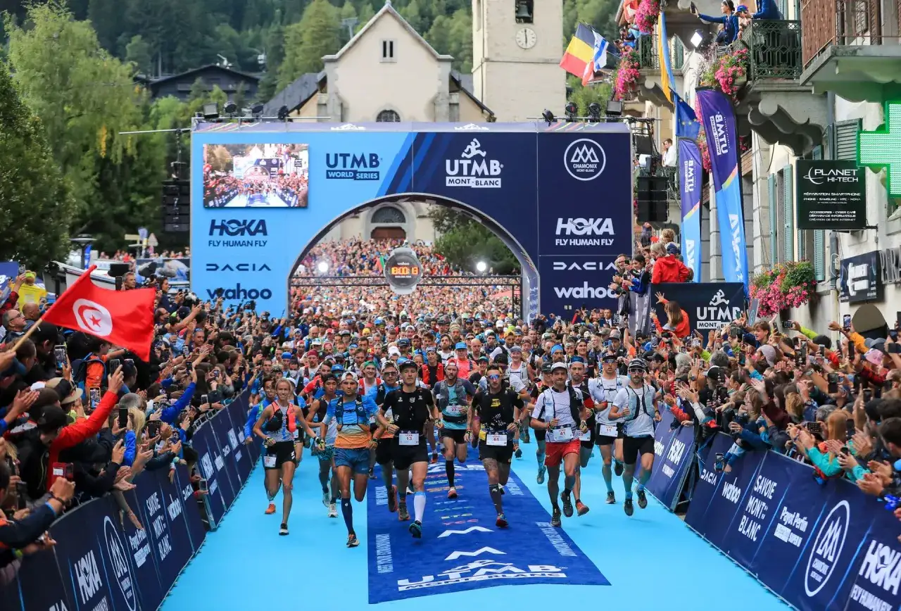 D&eacute;part massif de l'UTMB Mont-Blanc, le nombre de participants est impressionnant. La foule encourage les coureurs sous l'arche de d&eacute;part.