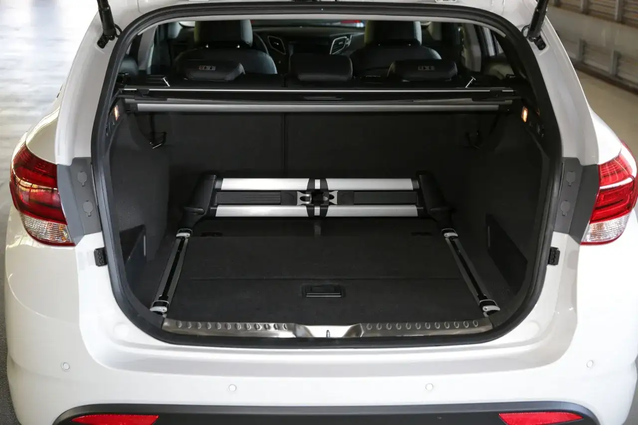 Biały Hyundai i40 z otwartym bagażnikiem. W środku złożona roleta i system mocowania ładunku. Wiele osób chwali ten model, czytając Hyundai i40 opinie.