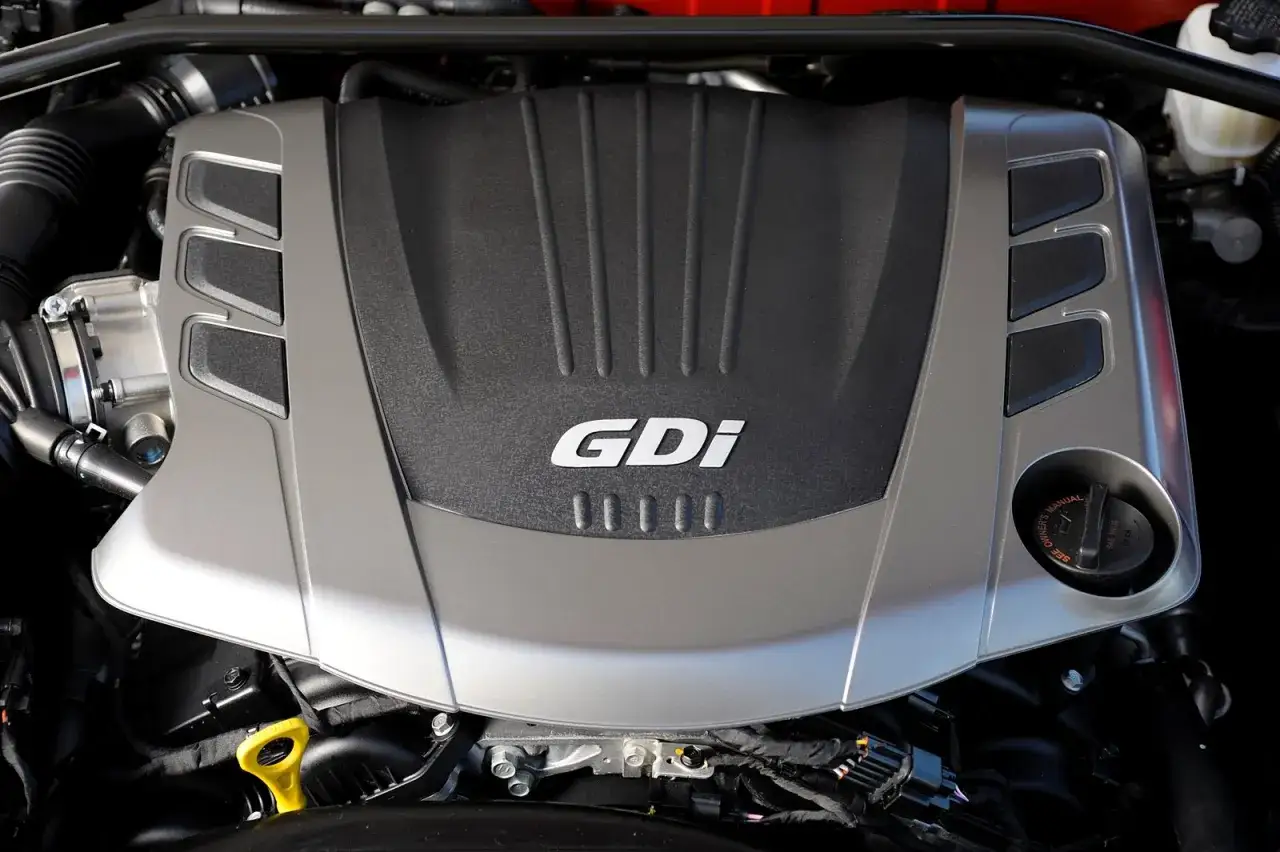 Silnik GDi w Hyundai Genesis Coupe. Widoczny metalowy wlot powietrza i osłona silnika z napisem GDi.