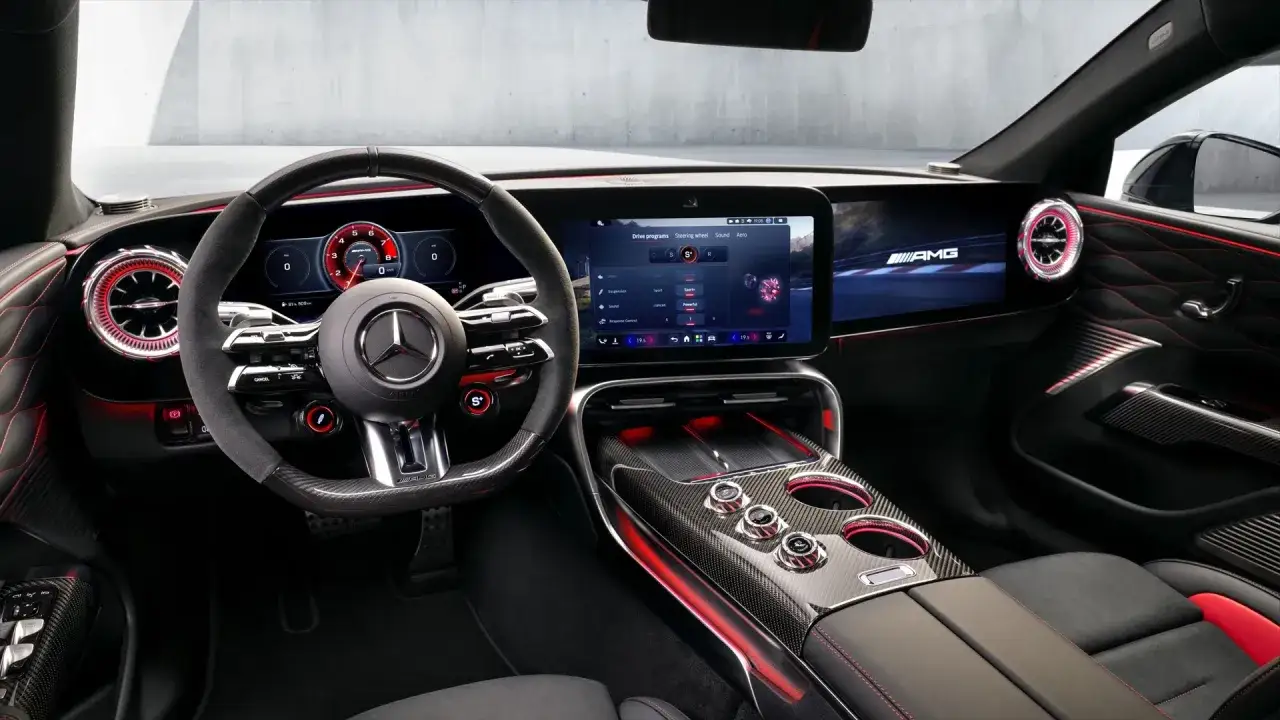 Wnętrze Mercedes GT 63 AMG: sportowa kierownica, cyfrowe zegary, duży ekran MBUX z programami jazdy i czerwone akcenty.