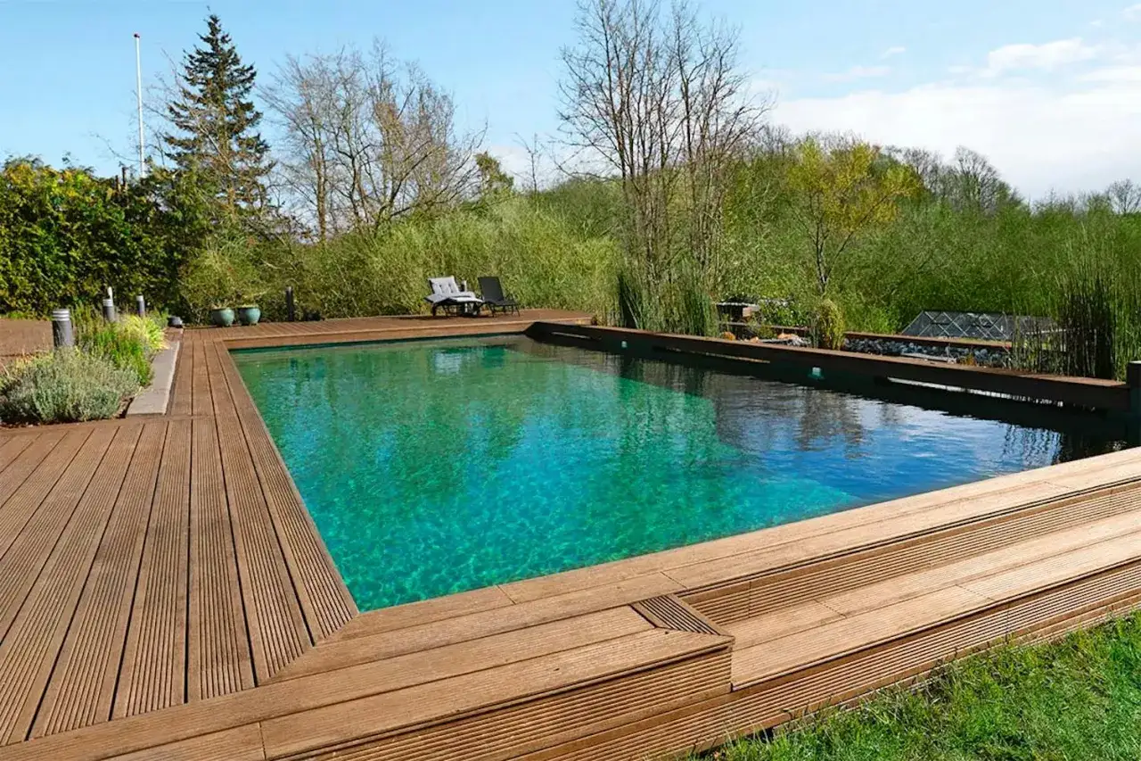 En vacker klorfri pool med träaltan och grönskande omgivning. Perfekt för avkoppling i naturen.