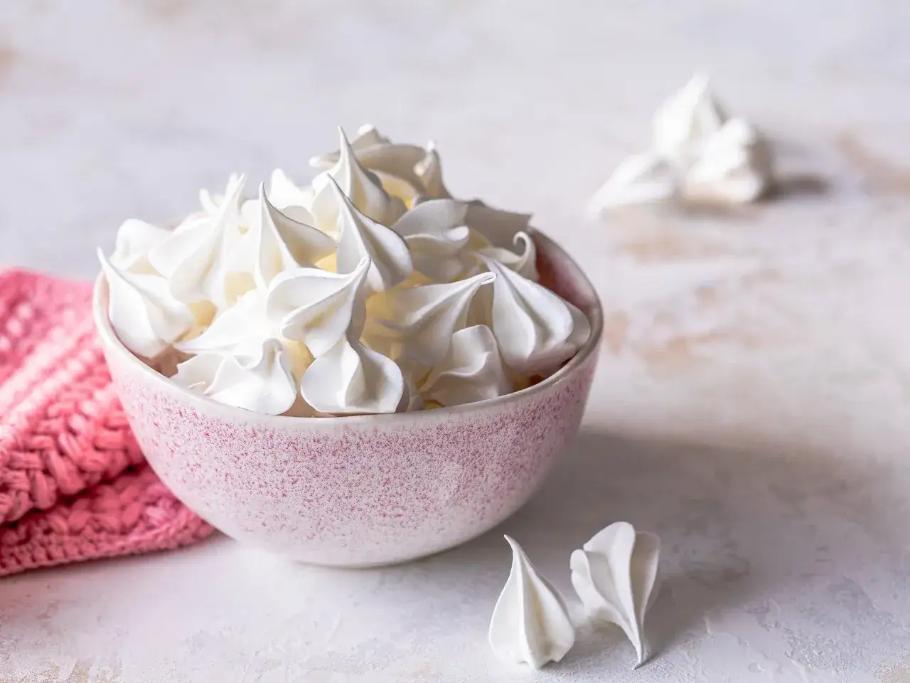 Schüssel voller luftiger Baisers, perfekt für ein einfaches Baiser Rezept. Daneben ein paar einzelne Baiser-Häppchen.