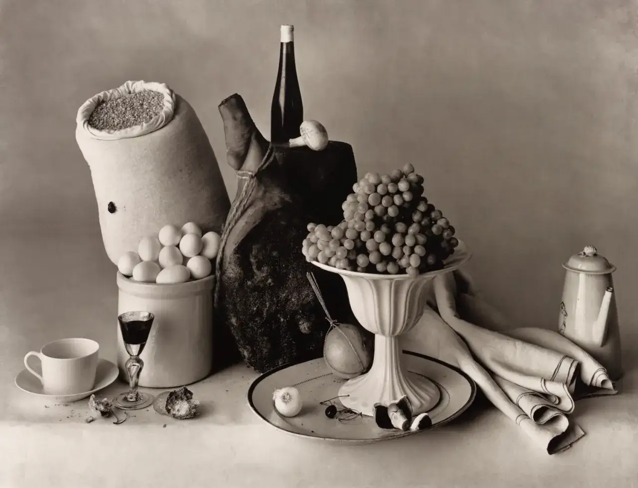 A classic still life arrangement, reminiscent of old masters, featuring grapes, eggs, a ham, and wine. This scene inspires still life artists.
