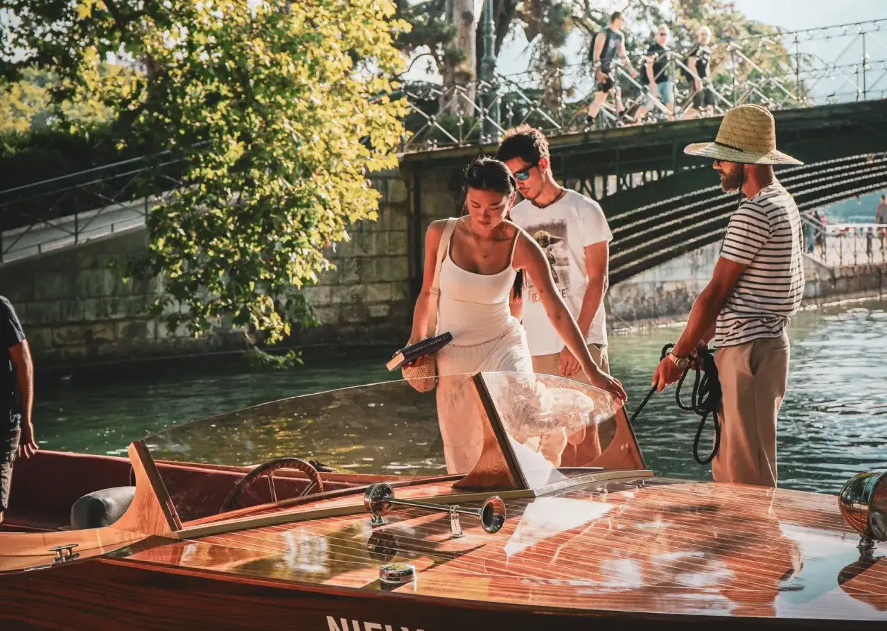 Un couple profite d'une activité à Annecy, montant dans un bateau en bois.