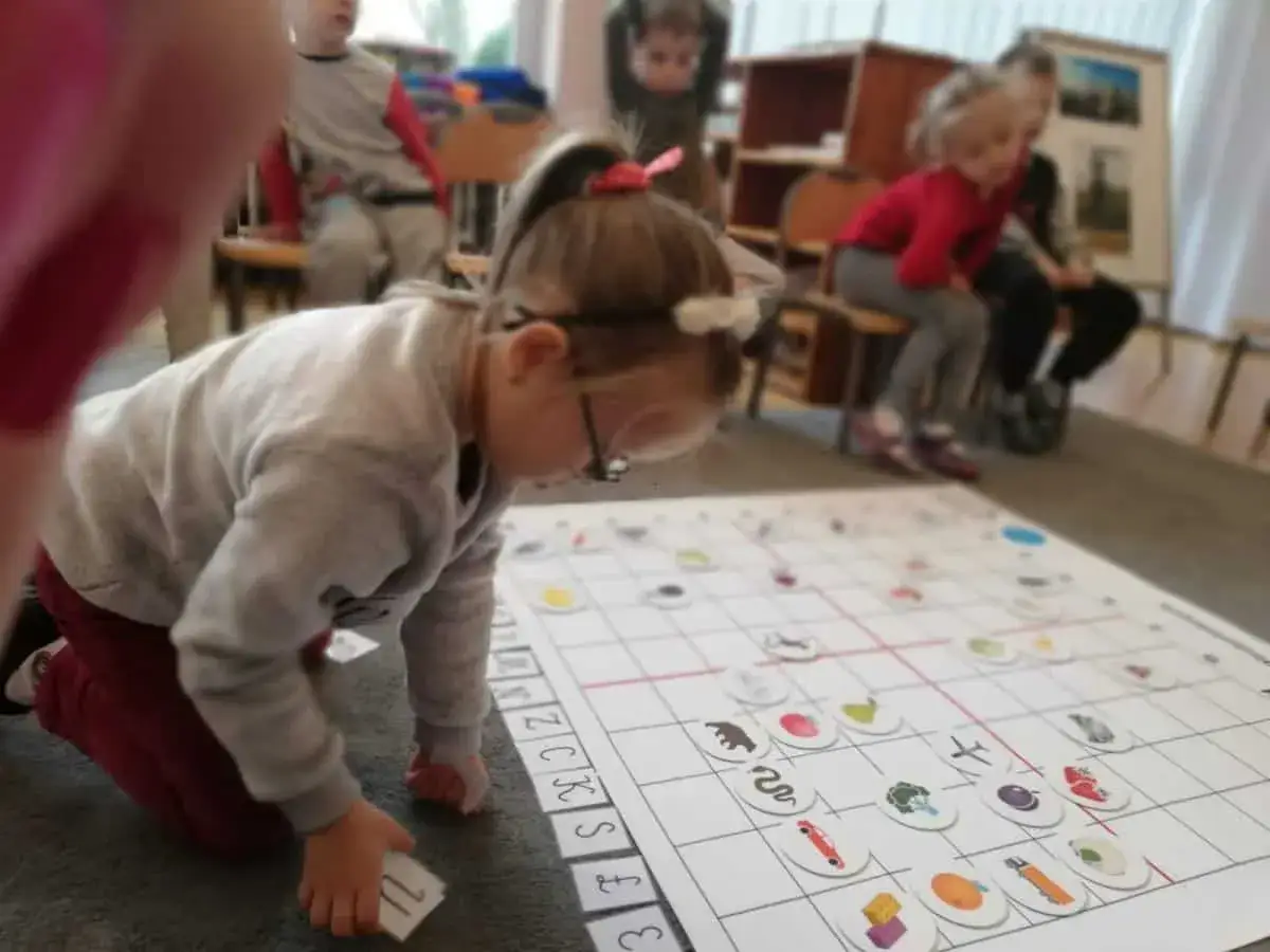 Dzieci uczą się programowania dla dzieci, układając karty z obrazkami na planszy.