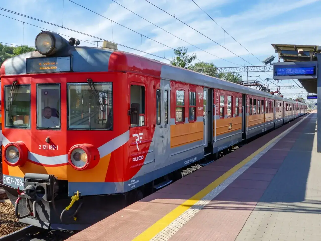 Czerwono-pomarańczowy pociąg Polregio czeka na pasażerów na stacji. To nasz pociąg do Kołobrzegu!
