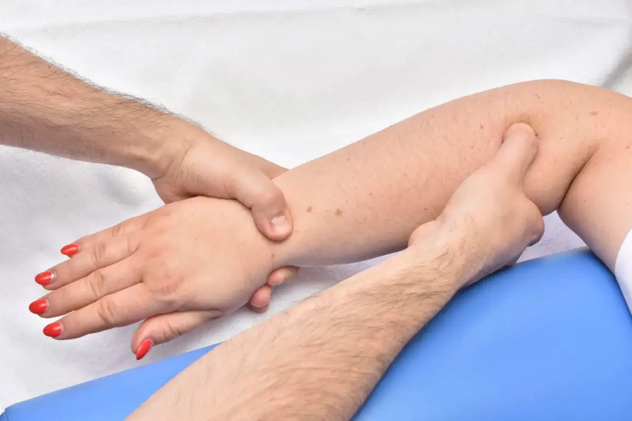 Delikatny masaż limfatyczny nóg, pokazujący techniki samopomocy. Dłonie terapeuty obejmują nogę, wykonując ruchy drenujące.