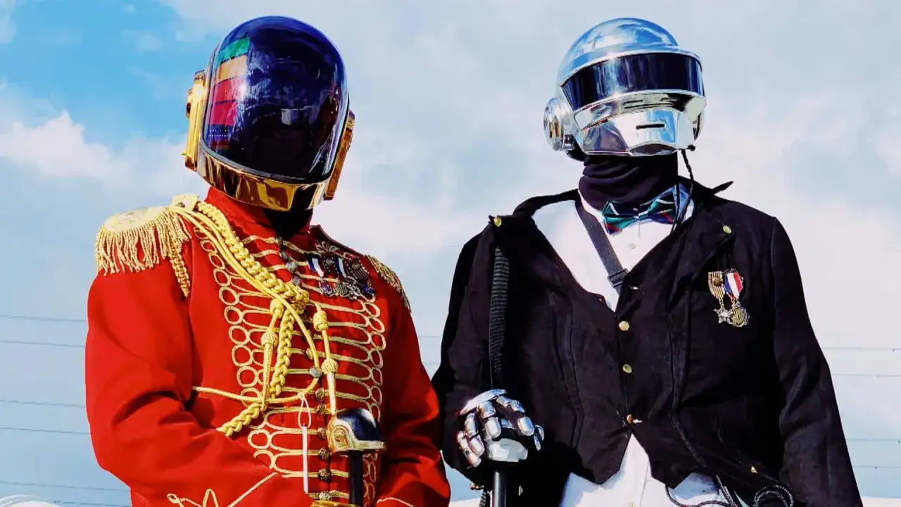 Tv&aring; medlemmar av Daft Punk i sina ikoniska hj&auml;lmar, en kl&auml;dd i en r&ouml;d milit&auml;rjacka med gulddetaljer, den andra i en svart kavaj med fluga.