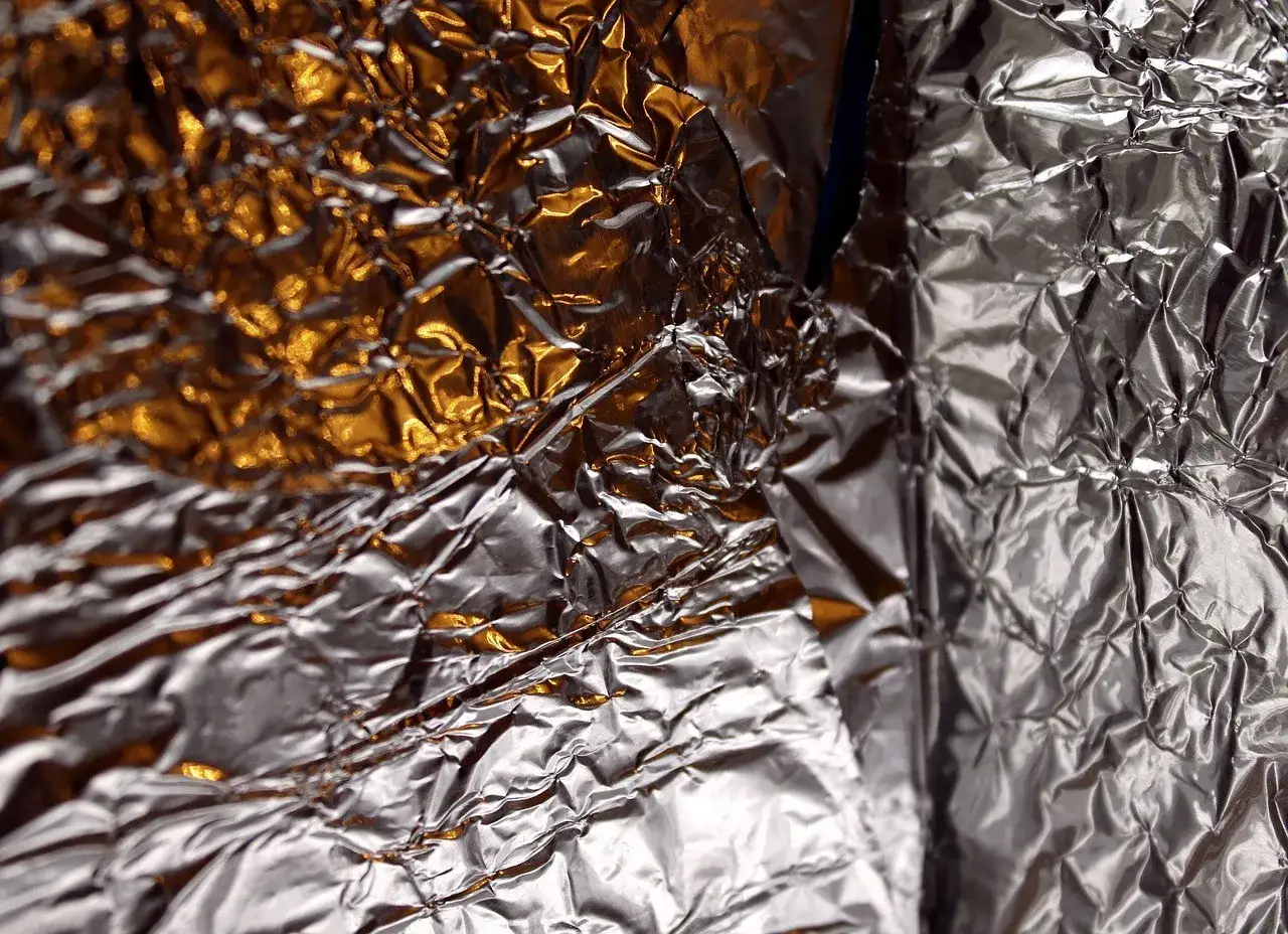 Zgnieciona folia aluminiowa, błyszcząca i odbijająca światło. Zastanawiasz się, gdzie wyrzucić folię aluminiową? Do pojemnika na metale i tworzywa sztuczne.