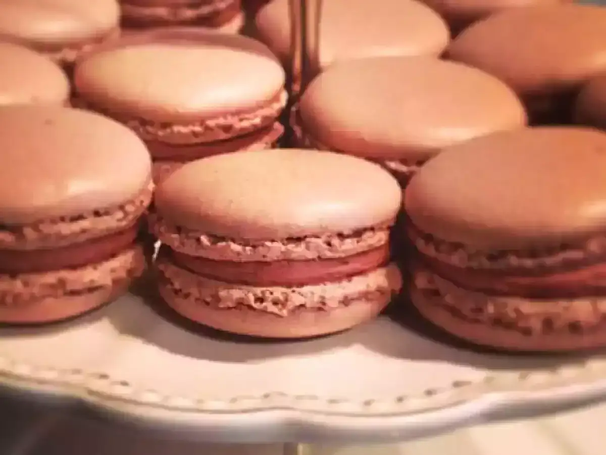 Gros plan sur des macarons au chocolat au lait, dispos&eacute;s sur une assiette blanche.