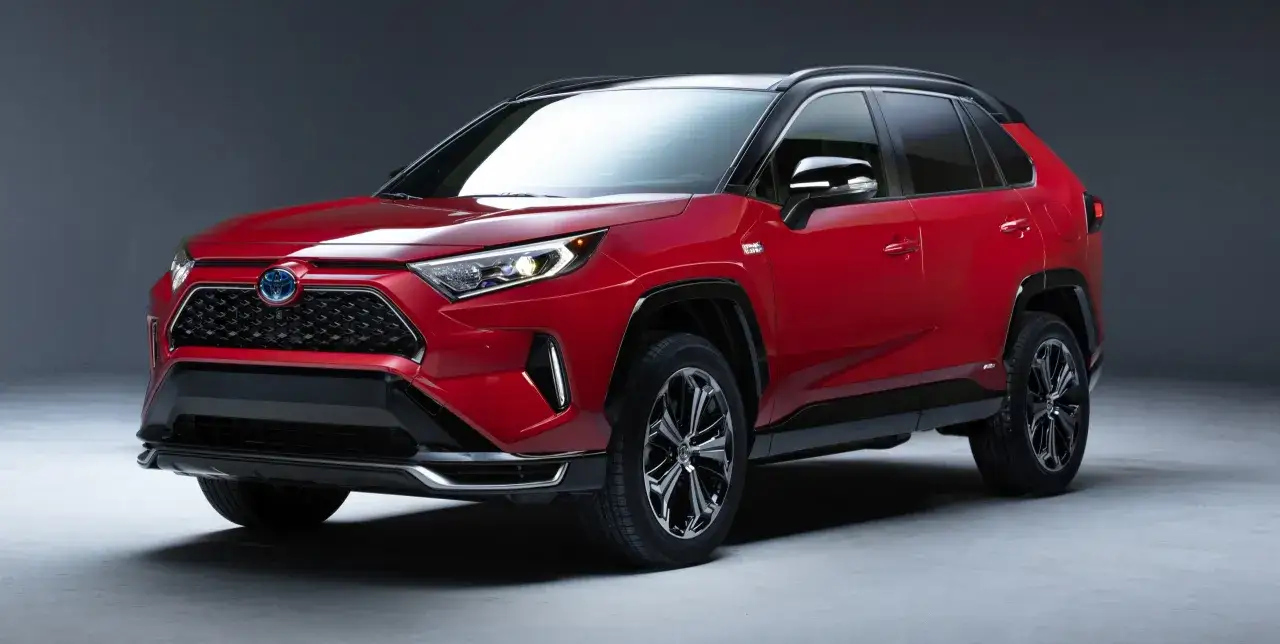 Czerwona Toyota RAV4 Hybrid, SUV z czarnym dachem. Zastanawiasz się, ile kosztuje Toyota RAV4 Hybrid?