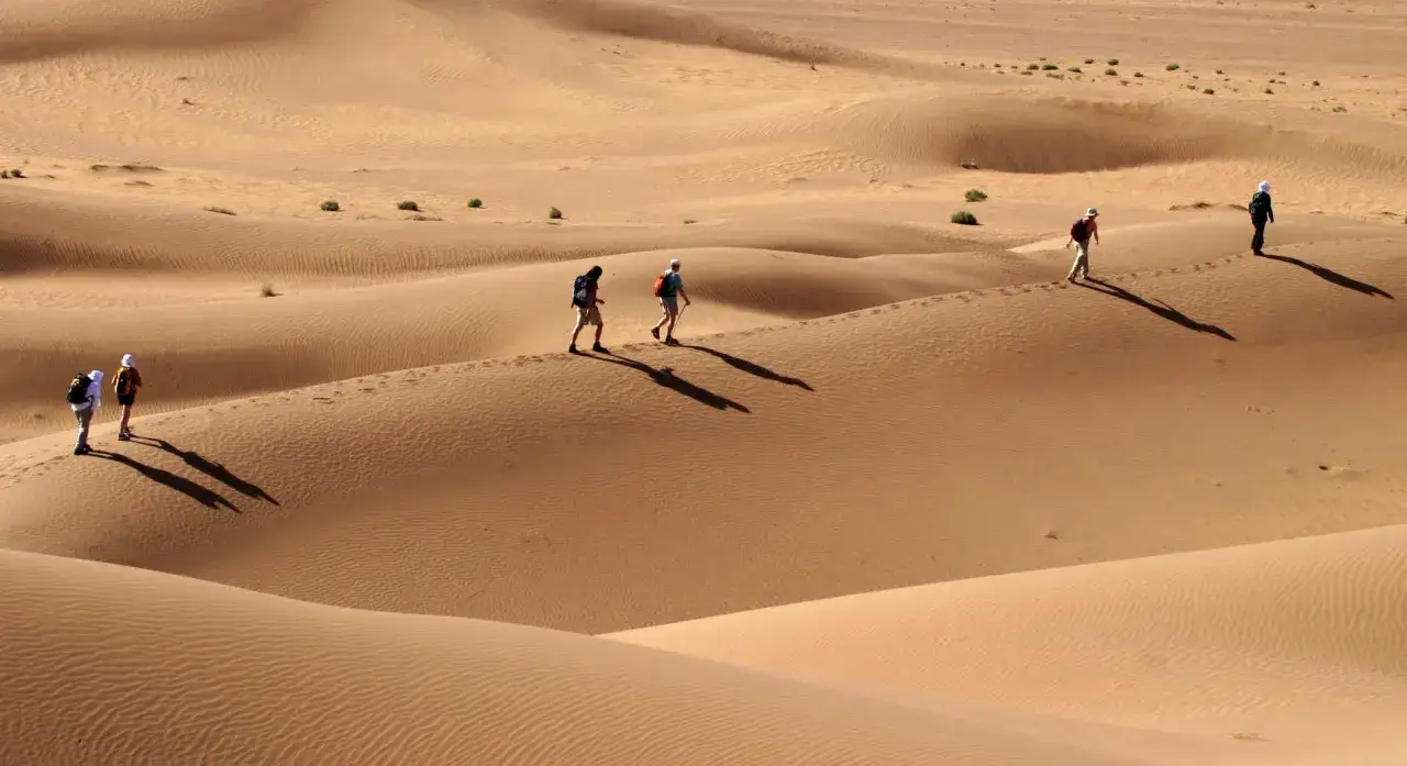 Un groupe de randonneurs s'aventure dans les dunes ondulantes du désert du Maroc pour un trek inoubliable.