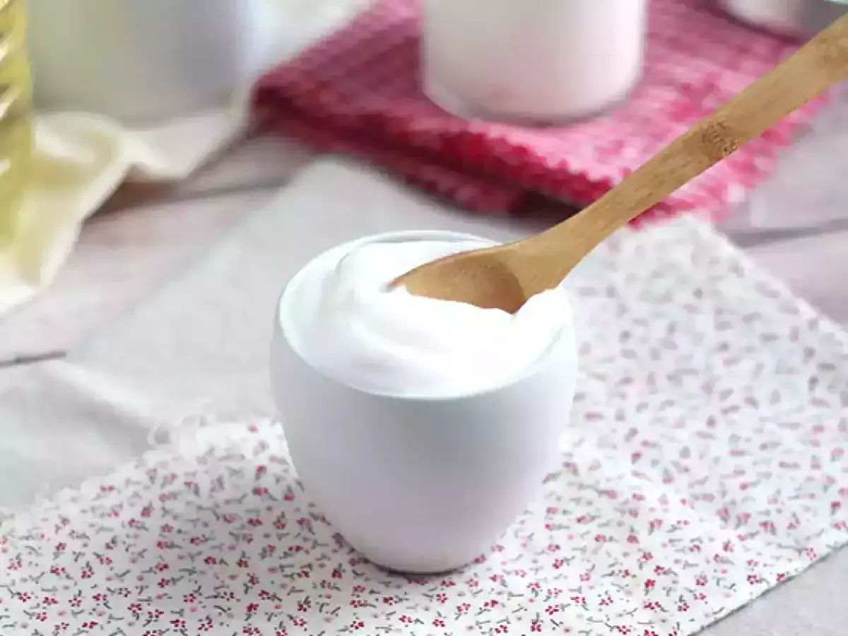 Cremige mayonnaise ohne ei in einer Schüssel, mit einem Holzlöffel.