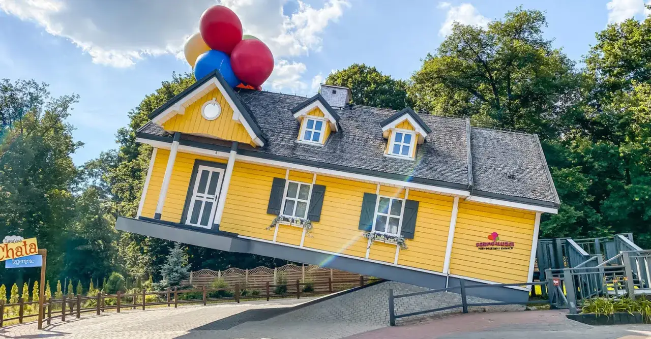Ż&oacute;łty domek na farmie iluzji unosi się dzięki balonom.