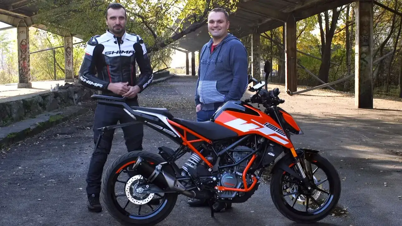 Dwóch mężczyzn obok pomarańczowo-czarnego KTM Duke 125. Rozmawiają o ktm duke 125 odblokowanie.