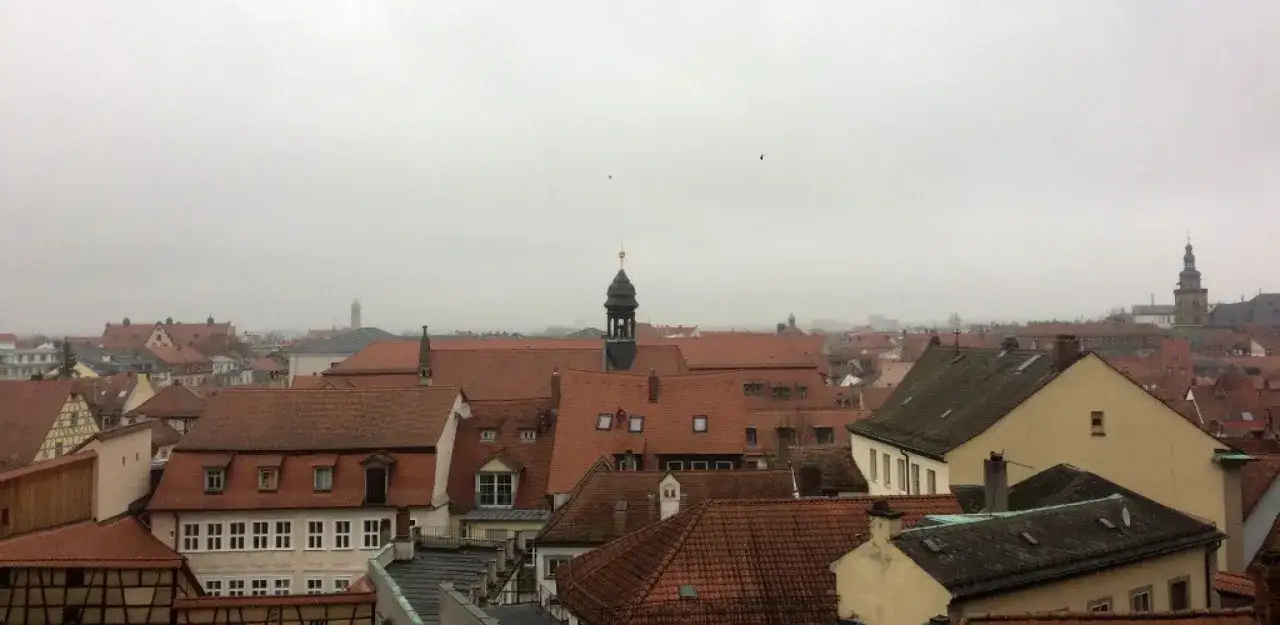 Dachlandschaft von Bamberg bei tr&uuml;bem Wetter. Entdecken Sie die **Bamberg Geheimtipps** zwischen den roten Ziegeld&auml;chern und Kircht&uuml;rmen.