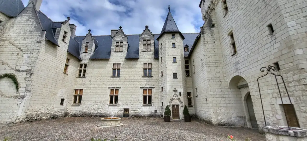 Cour intérieure du château du Rivau, avec sa façade en pierre blanche, ses toits d'ardoise et sa fontaine. Le propriétaire a su préserver l'authenticité du lieu.