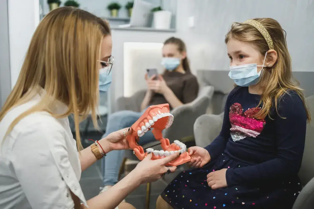 Dentystka pokazuje dziecku model szczęki, wyjaśniając działanie aparatu ruchomego.