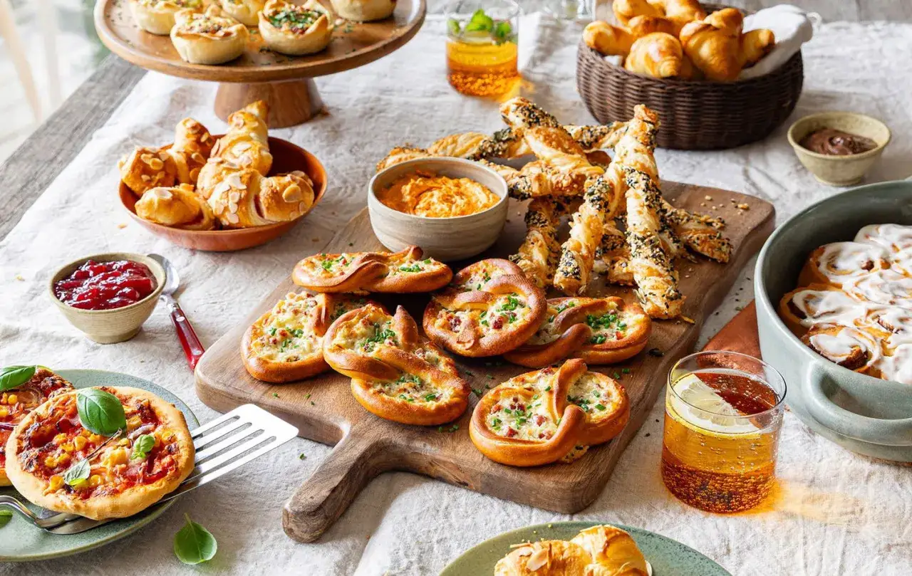 Leckere partyrezepte zum vorbereiten am vortag: Mini-Pizzen, Brezeln mit Speck, Blätterteigstangen und Zimtschnecken.