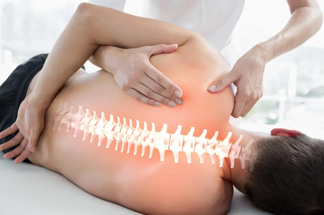 H&auml;nde eines Therapeuten behandeln den R&uuml;cken eines Mannes. Die Wirbels&auml;ule leuchtet. Einblicke in den Unterschied Osteopathie und Chiropraktiker.