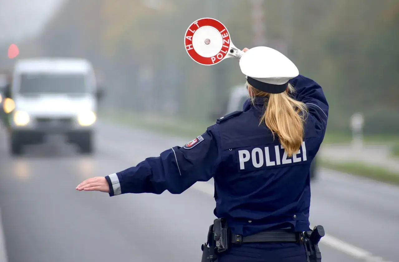 Polizistin stoppt Verkehr mit Stoppschild. Ein Fahrer mit 0,3 Promille muss anhalten.