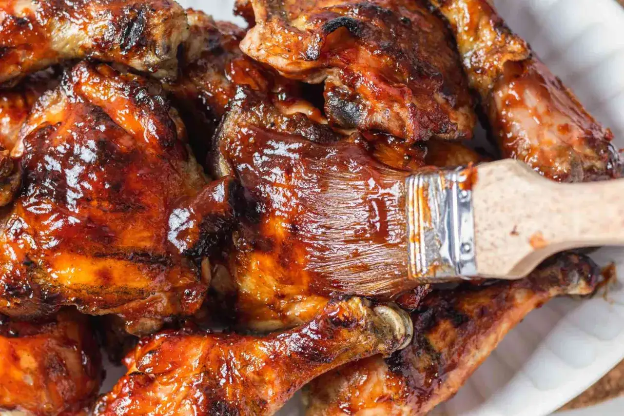 En pensel applicerar glaze p&aring; saftig, grillad kyckling. Perfekt f&ouml;r en sommarkv&auml;ll med grillning av kyckling.