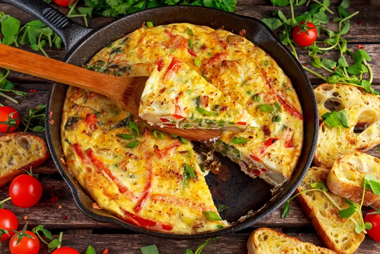 Herzhafte Frittata in der Pfanne oder im Ofen, mit Gem&uuml;se und Brot serviert.