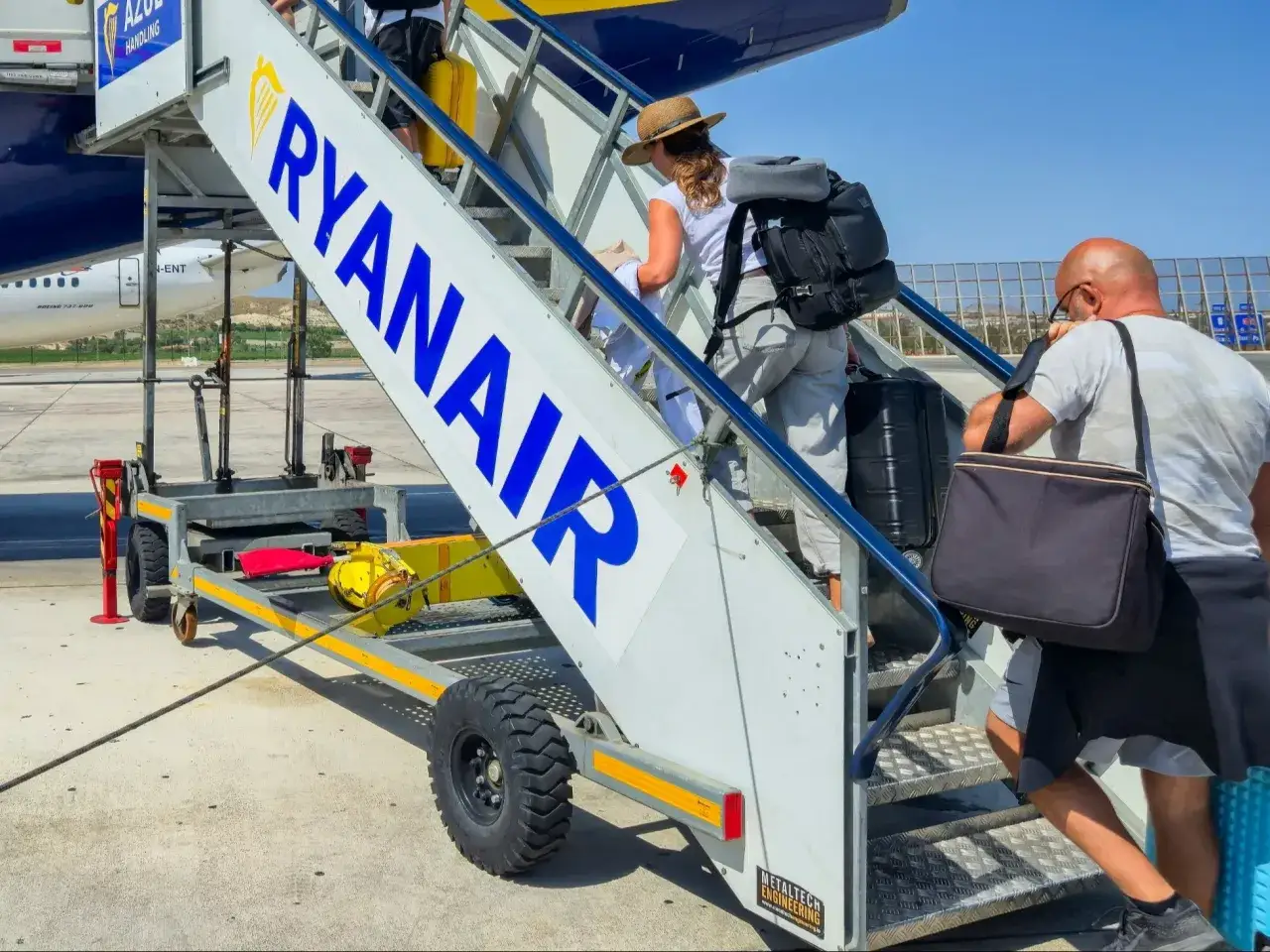 Ludzie wchodzą po schodkach na pokład samolotu Ryanair. Uniknij kary za niestawienie się na lot, bądź na czas!