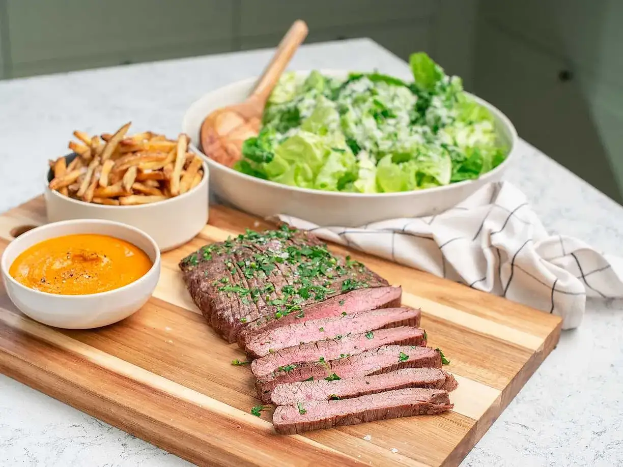Skivad biff med pommes frites, sallad och en sk&aring;l med kr&auml;mig bbq s&aring;s.