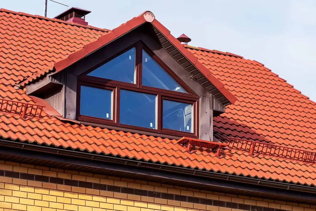 Dachgaube mit dreieckigem Fenster auf rotem Ziegeldach. Informieren Sie sich &uuml;ber Dachgaube Kosten f&uuml;r Ihr Haus.