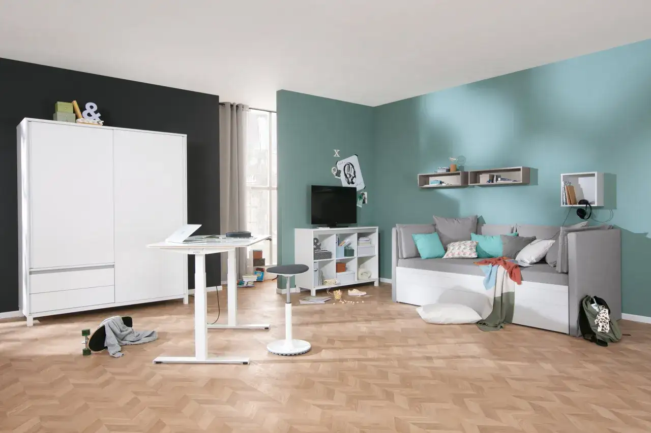 Moderne Jugendzimmer Ideen: Ein wei&szlig;er Schrank, h&ouml;henverstellbarer Schreibtisch, Sofa, TV-M&ouml;bel und Skateboard schaffen einen coolen Raum.