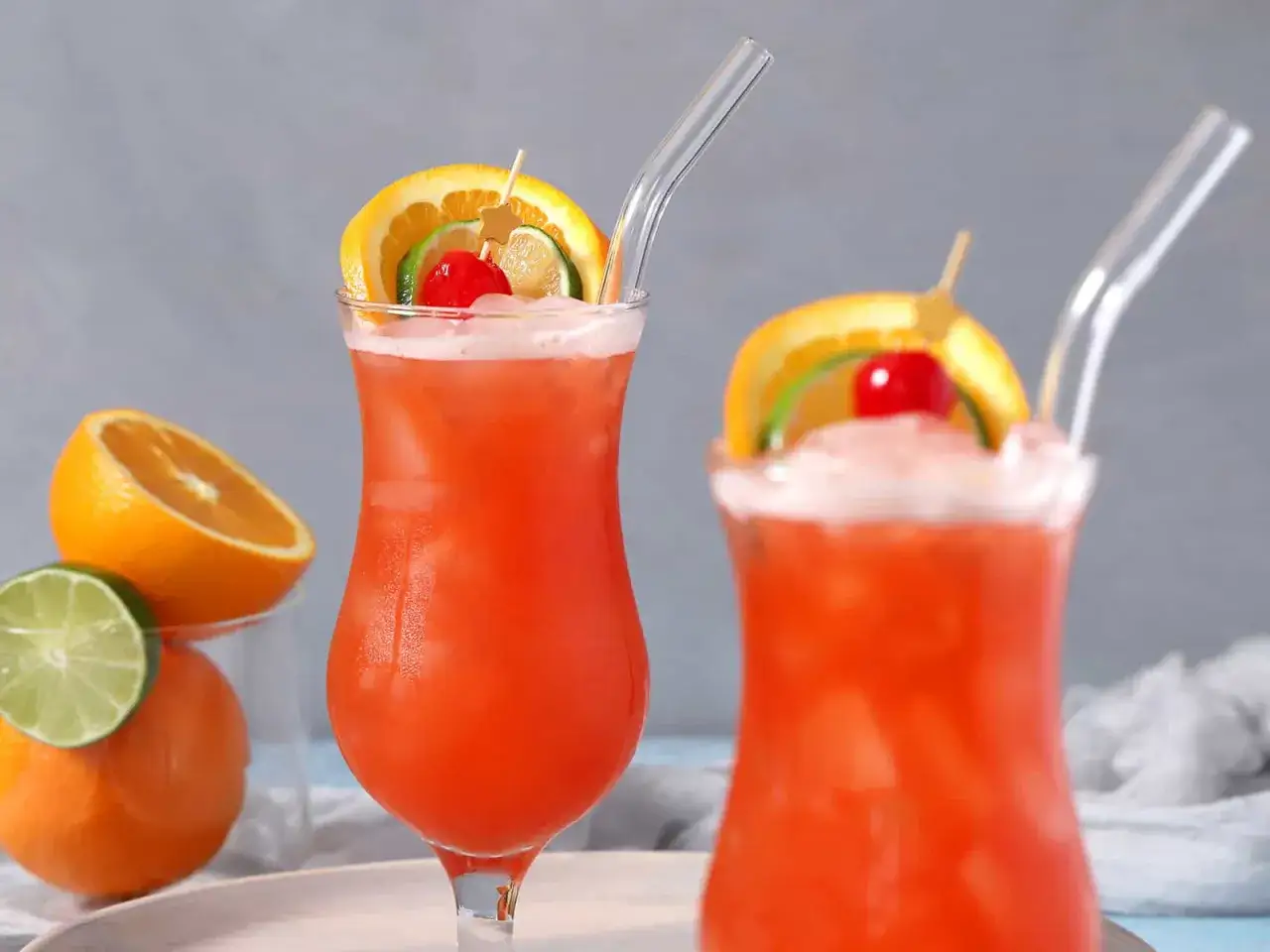 Dwa orzeźwiające drinki z rumem, ozdobione plasterkami pomarańczy, limonki i wiśnią. Idealne na letnie popołudnie.