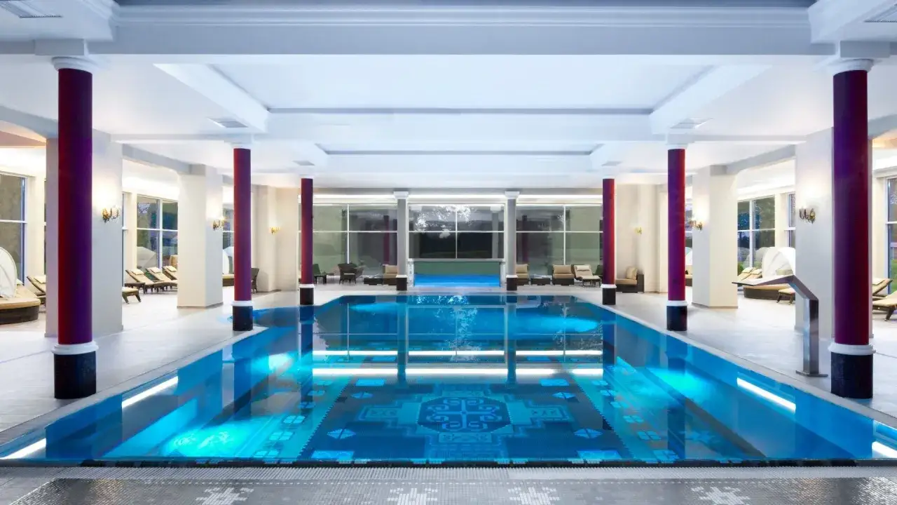 Luksusowe spa do 100 km od Warszawy. Basen z niebieską wodą, leżaki i eleganckie kolumny tworzą atmosferę relaksu.