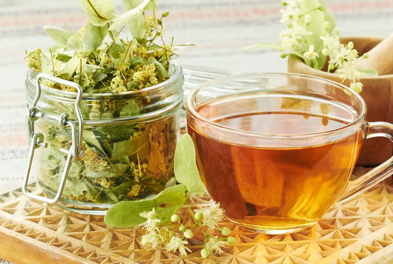Infusion de tilleul dans une tasse, avec des fleurs et des feuilles s&eacute;ch&eacute;es. Bien que le tilleul soit r&eacute;put&eacute; pour ses bienfaits, il peut y avoir un effet secondaire &agrave; consid&eacute;rer.